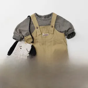 Flat lay of khaki toddler overalls with Luck patch and striped long sleeve t-shirt