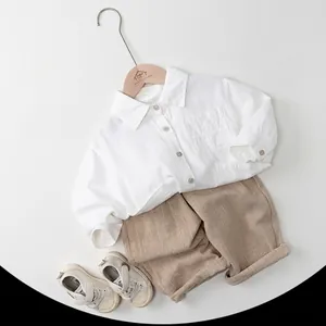 Ensemble printemps enfant avec chemise blanche, short rayé beige et baskets à scratch
