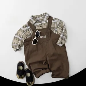 Flat lay of brown kids overalls with Luck embroidery and plaid shirt for toddlers