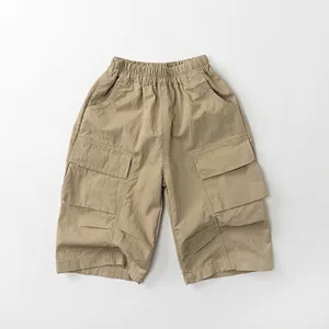 Detail of khaki kids cargo shorts featuring elastic waist and large pleated side pockets