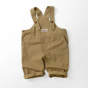 Detail of khaki cotton kids overalls with adjustable straps and Luck embroidery