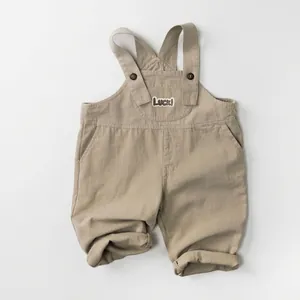 Detail of khaki kids overalls featuring Luck! patch and high-quality cotton texture