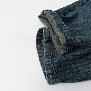 Vue détaillée du denim à rayures bleu foncé montrant la texture épaisse et l'ourlet plié