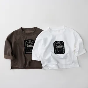 Detail of pure cotton kids long-sleeved t-shirts with square graphic prints and side slits