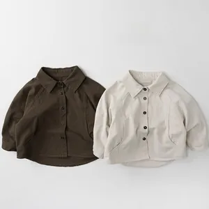 Flat lay of cotton linen kids shirts in dark coffee and beige with buttoned collars