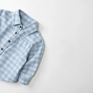 Detail of blue gingham plaid long sleeve shirt with front pocket and round buttons
