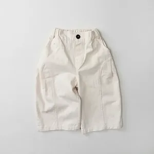 Detail of off-white kids wide-leg pants featuring elastic waist and black button detail