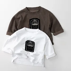 Detailed view of kids cotton t-shirts in white and brown with artistic chest print