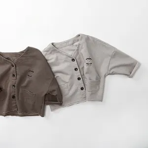 Detail of V-neck kids cardigans featuring apple embroidery and raw edge hem design