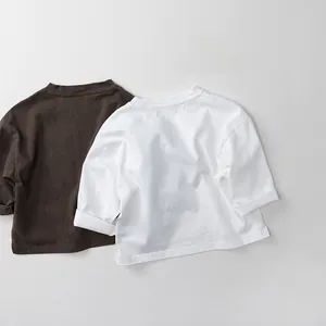 Detail of soft cotton kids long sleeve shirts with rolled cuffs in brown and white