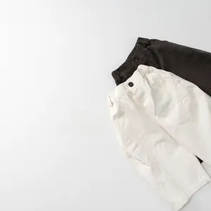 Detail of elastic waist with buttons on beige and brown wide-leg cotton pants for kids