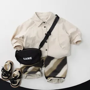 Flat lay of beige long sleeve shirt and striped pants with matching shoes and bag
