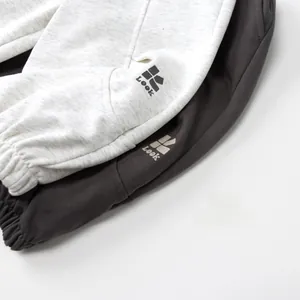 Details der Rippbündchen und des Logo-Prints auf grauen Baumwoll-Jogginghosen