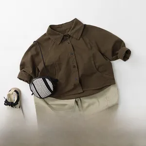Flat lay of a children fashion set with brown button-up shirt and gray casual trousers