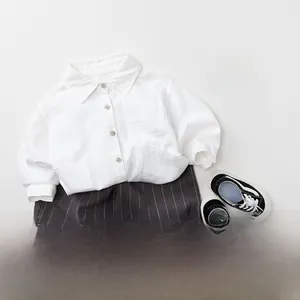 Mise à plat de chemise enfant en lin, short gris à rayures et baskets en toile