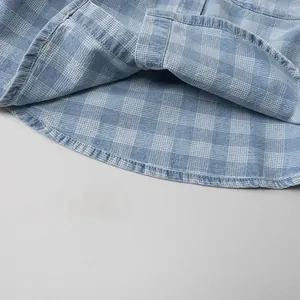 Macro view of blue plaid denim shirt fabric with detailed stitching and soft cotton texture