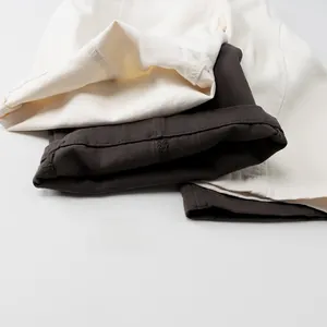 Detailed close-up of folded leg hems on beige and dark grey cotton trousers for kids