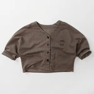 Detail of kids brown V-neck cardigan with apple print and raw cut hem for a minimalist look