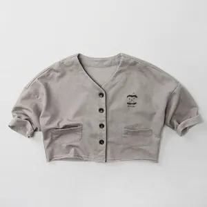 Detail of grey knitted kids cardigan with V-neck, black buttons and apple embroidery