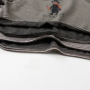 Close-up of striped cotton fabric with a cute cartoon bear print and decorative text