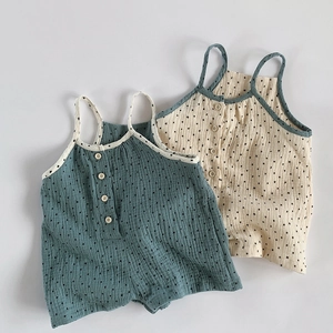 Close-up of soft cotton gauze baby rompers featuring delicate star patterns and wooden buttons