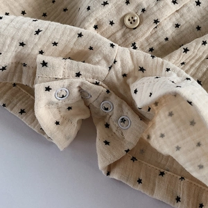 Close-up of star print baby romper with silver metal snaps and soft cotton gauze fabric