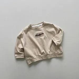 Dettaglio felpa in cotone beige con grafiche di ghiande e testo momo memo sul petto