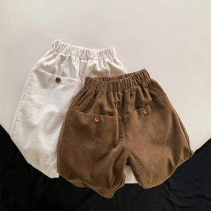 Detail view of children corduroy pants in cream and brown with elastic waist and buttons