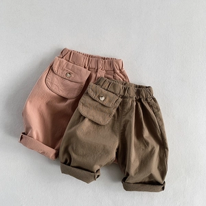 Detail of loose-fit cotton linen pants with elastic waist and buttoned pockets for kids