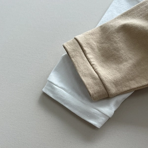 Dettaglio dei polsini in maglia di morbido cotone bianco e kaki per maglie da bambino