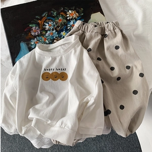 Detalle de camiseta blanca de manga larga en algodón con diseño de sonrisa y pantalón de lunares