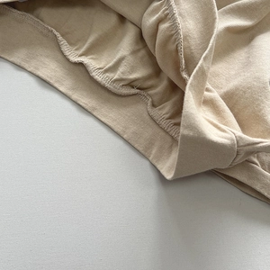 Dettaglio dell'orlo in cotone a coste beige con elastico in vita di qualità