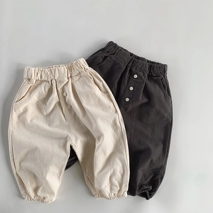 Detail of loose-fit cotton linen toddler trousers with elastic waist and button accents