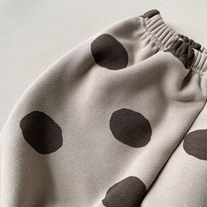 Macro shot of cream-colored kids polka dot pants featuring wide elastic waistband details