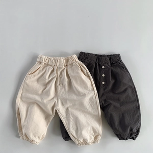 Detail of loose-fit cotton linen kids trousers with elastic waist and button accents