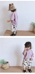 Detail view of girl's purple heart t-shirt and white polka dot wide-leg pants