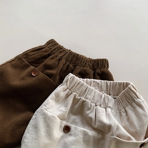 Close-up of elastic waistband and decorative buttons on corduroy toddler trousers