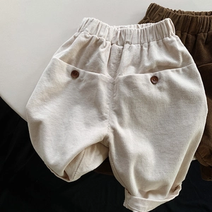 Detail of high-waist corduroy kids pants with elastic waistband and decorative buttons