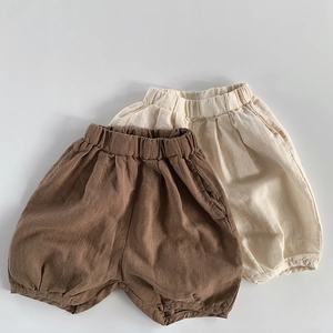 Flat lay detail of kids linen harem shorts in brown and beige colors with elastic waist