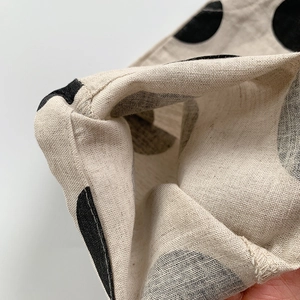 Vue macro détaillée du tissu en lin beige à pois noirs avec des bords ourlés et une texture