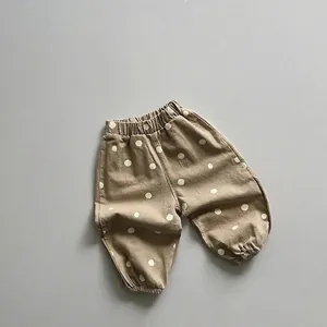 Détail d'un pantalon à pois pour enfants avec taille élastique et chevilles resserrées marron