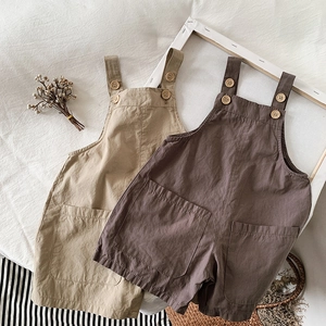 Flat lay of cotton linen baby overalls in khaki and brown with natural button details