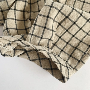Detailed macro view of linen-cotton fabric texture and hem stitching on plaid shorts