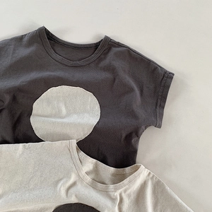 Close-up of minimalist kids' cotton T-shirts with contrasting circle patch detailing