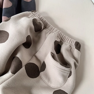 Close-up of beige thermal children's trousers with large brown polka dots and side pocket