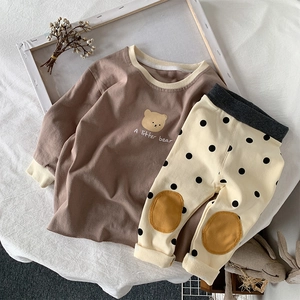 Detailed flat lay of toddler cotton set featuring bear print top and polka dot pants