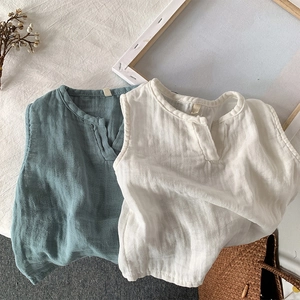 Gilet in cotone traspirante per bambini in blu-grigio e beige disposti in piano su tela