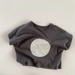 Detail of dark grey cotton T-shirt featuring a white round patch and loose shoulder fit