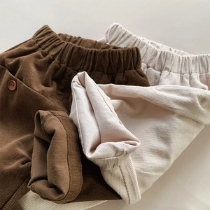 Detail of children corduroy pants featuring elastic waistbands and decorative side buttons