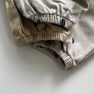 Gros plan des poignets élastiques sur pantalon enfant à pois montrant la texture sergé